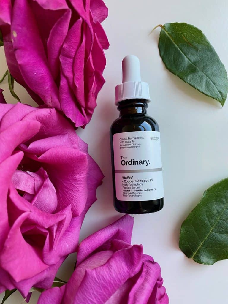 The Ordinary Buffet + Copper Peptides 1% serum next to roses